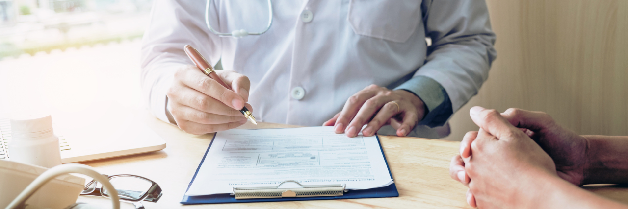 Repairing Broken Trust in the Doctor-Patient Relationship Doctor writing on chart with patient sitting nearby.