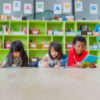 Children in classroom on floor reading books.