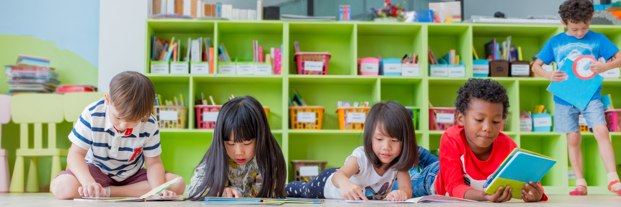 Supporting Students on the Autism Spectrum Children in classroom on floor reading books.