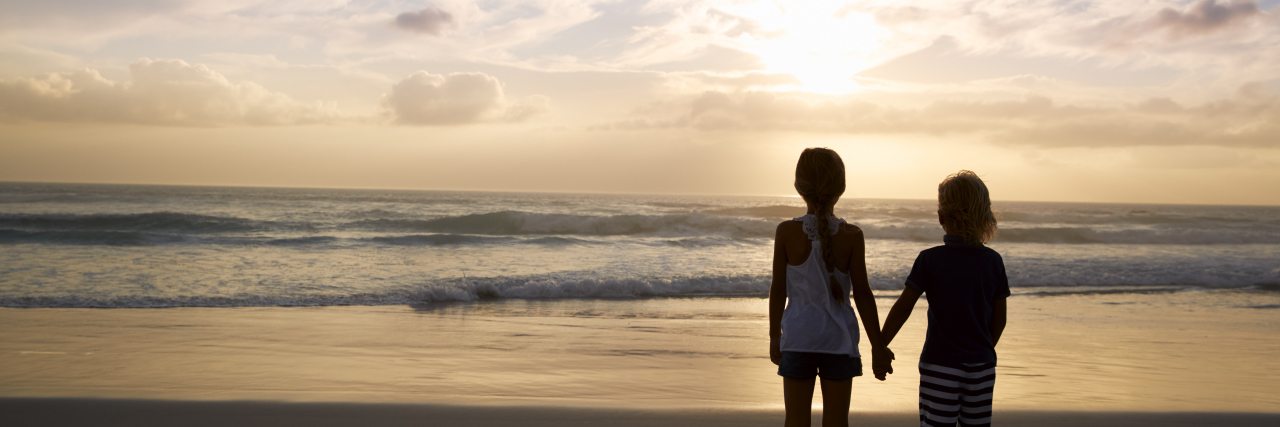 Supporting a Sibling With Autism Children, brother and sister holding hands on the beach.