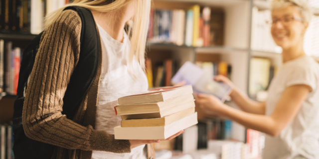 close-up of a girl carrying books and another woman talking to her in a bookstore