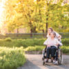 lderly grandmother in wheelchair with an adult granddaughter outside in spring nature.