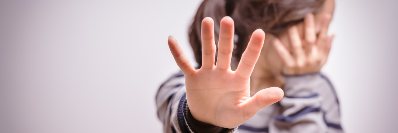 The R-Word Is Never Appropriate, and It Causes Harm Woman holding up hand with "stop" written on it.