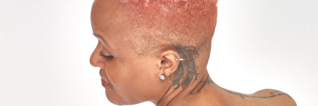 Keisha, African-American woman with pink hair and tattoos.