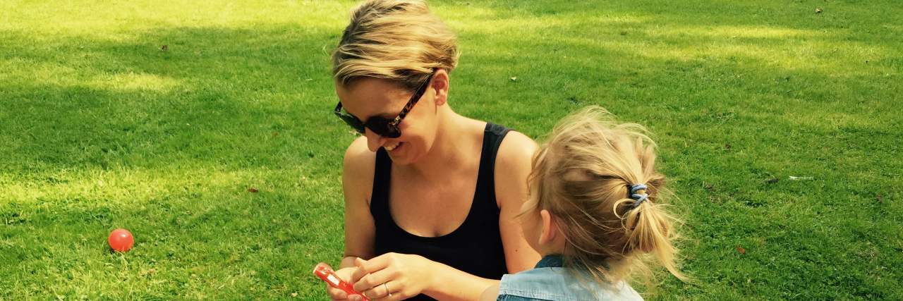 Ways to Survive and Enjoy Mother’s Day With Postpartum Depression a mother sitting with her daughter on a picnic blanket.