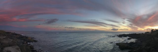 panoramic photo of a sunset over the ocean, taken from the top of a cliff
