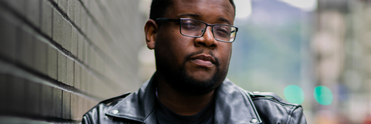 How I Publicly Destroyed My Life During My First Manic Episode photo of man wearing leather jacket leaning against wall with hand on wrist