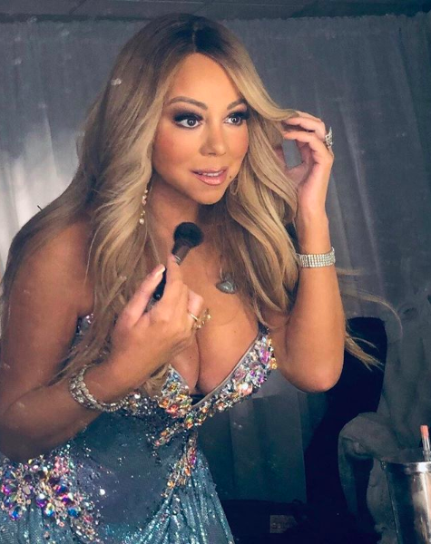 Mariah Carey looking in a mirror and putting on makeup