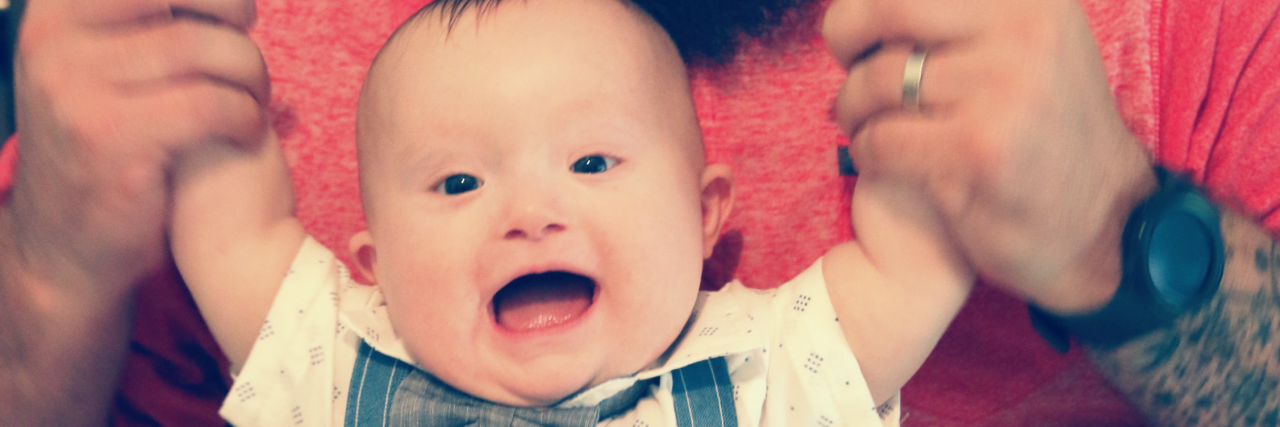 Confessions of a Dad Whose Child Has Down Syndrome Dad standing behind son holding him by the arms helping him stand.