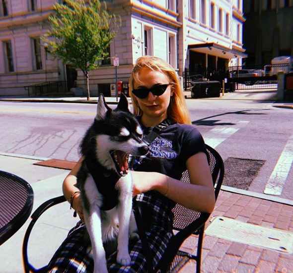 Sophie Turner sitting outside with a dog on her lap
