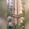 woman climbing down outside of tall building