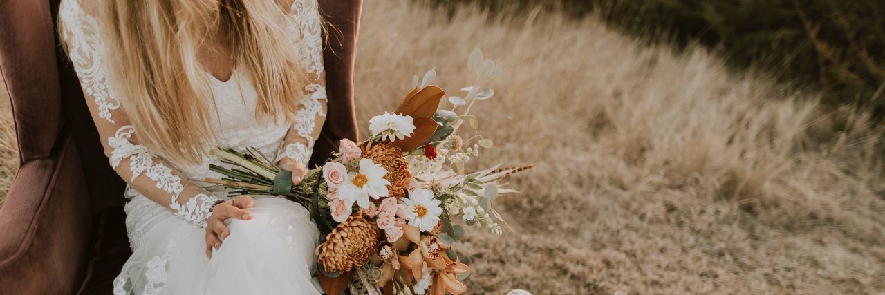 photo of woman sitting on chair in wedding dress holding bouquet