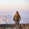 woman sitting on ledge looking at city skyline