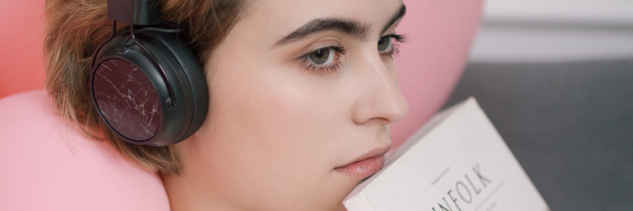 If You Feel Like You Can't Go On, Read This woman with headphones on reading a magazine, staring off into the distance