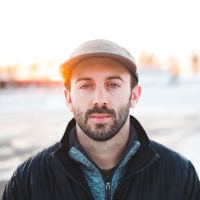 photo of man with beard and hat looking serious into camera
