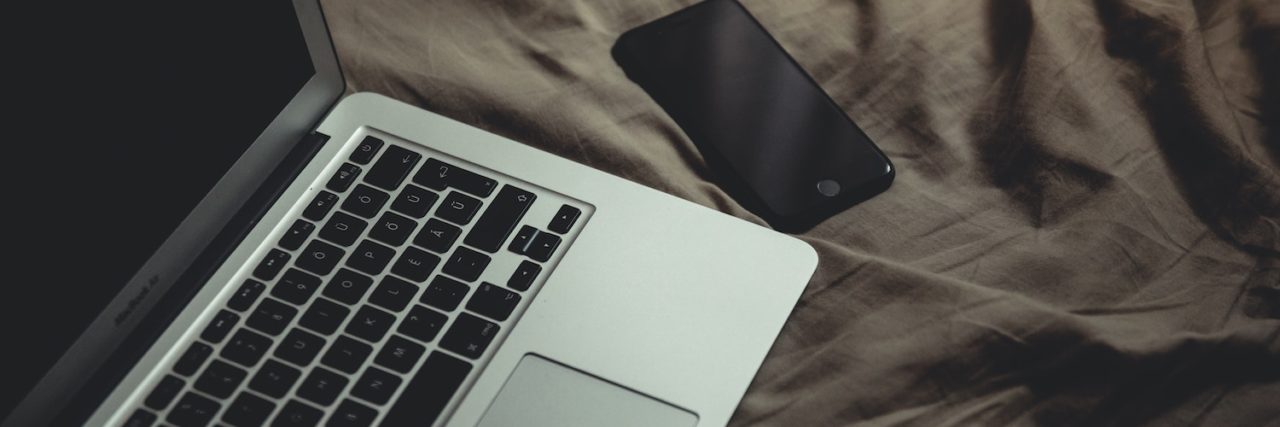 7 Work-From-Home Part-Time Jobs Available This April Open laptop next to a smartphone on a brown blanket