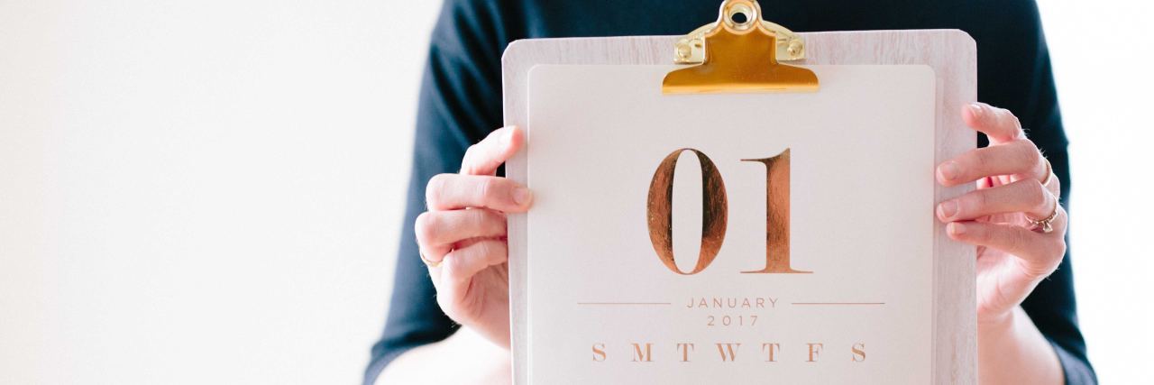 photo of woman holding up calendar showing first page in january