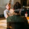 photo taken from behind woman sitting in front of slightly blurred man in conversation behind glass at office table