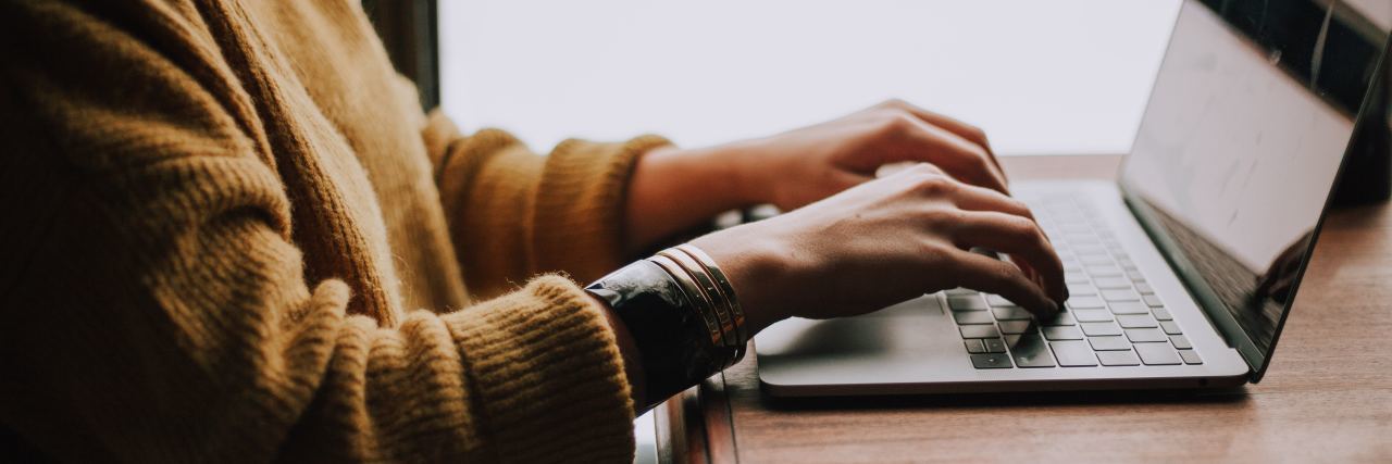 How My Boss Reacted When I Told Her About My Bipolar Disorder close up photo of person's hands on laptop typing with yellow seater visible