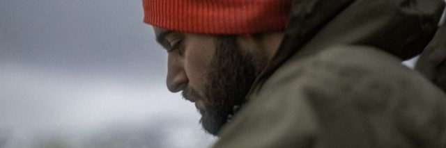 photo of man wearing red hat with his eyes lowered in sadness or mourning