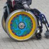 Manual wheelchair user with colorfully-decorated wheels.