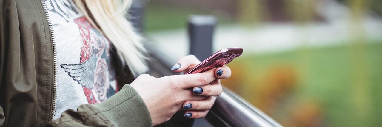 I'm Done Making Excuses for the Texts I Ignore When I'm Depressed A woman standing outside, holding a phone