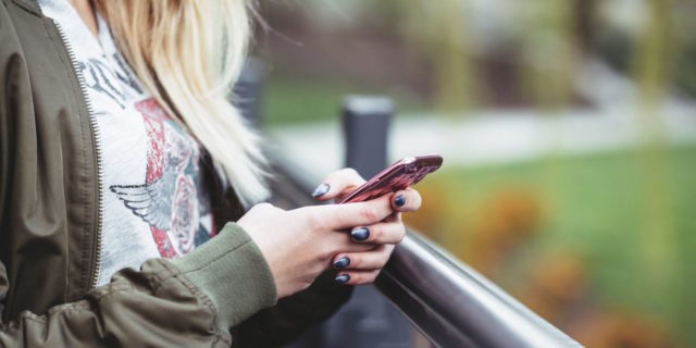 A woman standing outside, holding a phone