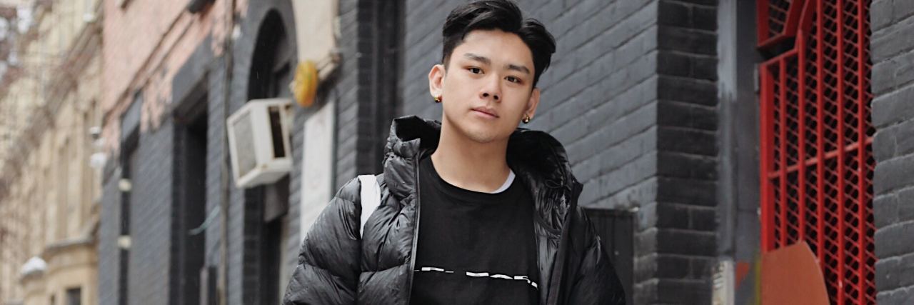 The Chinese Custom of Mianzi Affected My Mental Health photo of young asian man standing in street with hands in pockets and looking at camera