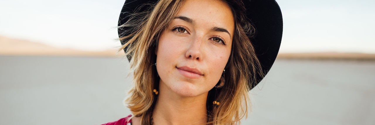 What I Learned About Being Depressed and Anxious in My 20s A young woman standing outside, wearing a hat