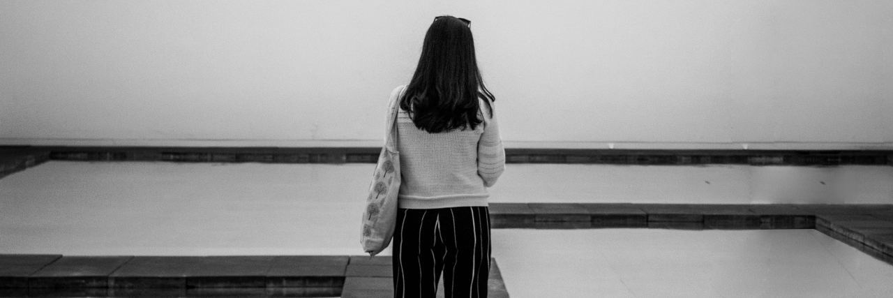 What It's Really Like to Have Fibromyalgia black and white photo of woman standing on walkway between square pools of still water