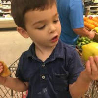 Little boy with autism holding a lemon at the supermarket.