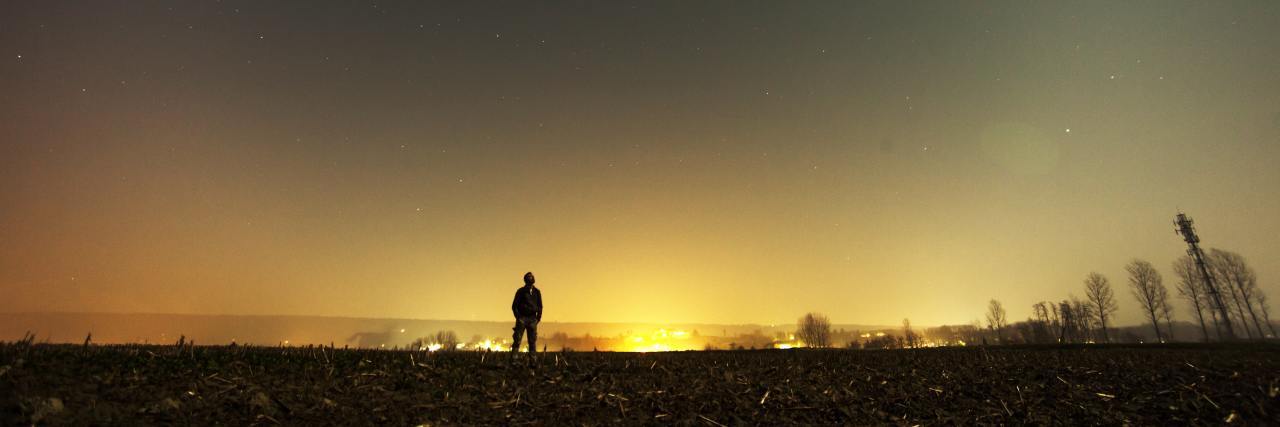 man outside far away with night sky and setting sun