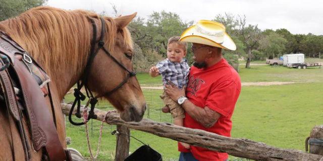 Burn survivor introducing his child to a horse.