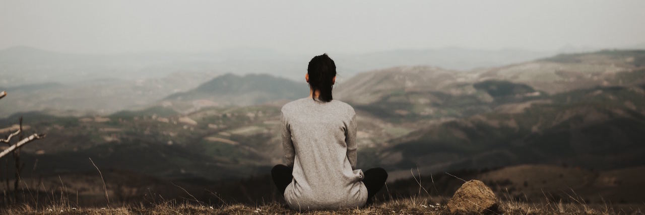 Chronic Illness and Feeling Lonely A woman sitting on a mountain top by herself