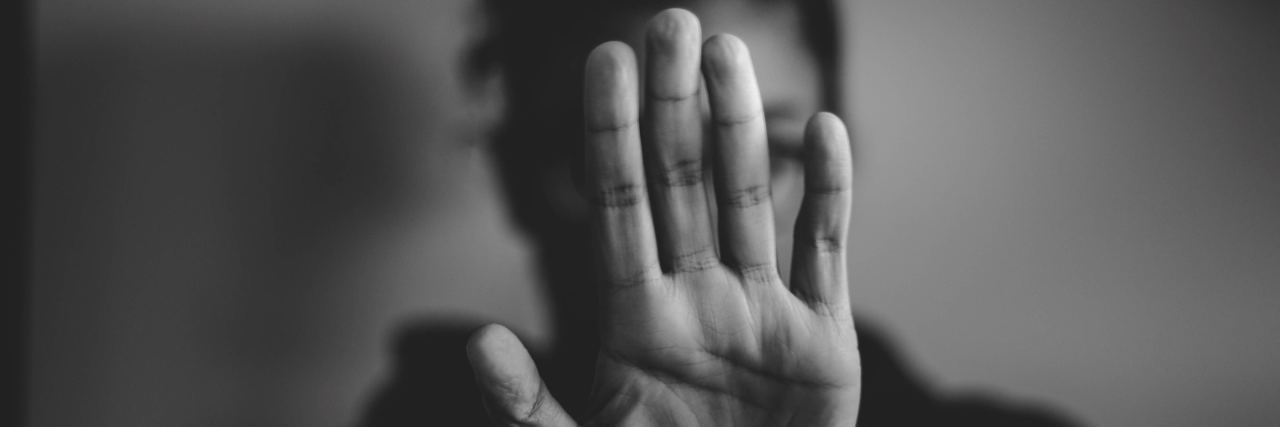 PTSD and Self-Care Doesn't Make Me Selfish black and white photo of woman holding up hand at camera covering face