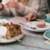 close up photo of people eating dessert and drinking coffee with items on table