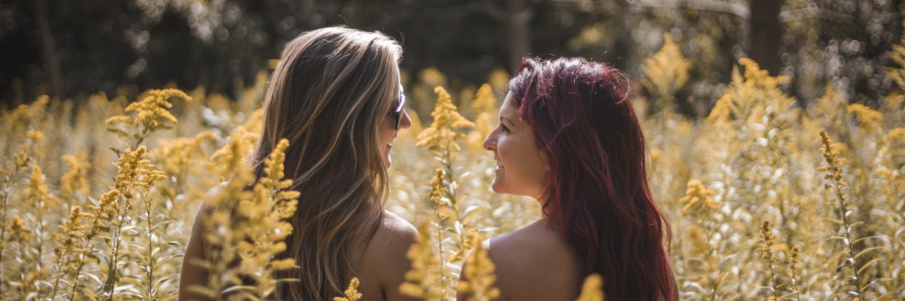 photo of two women sitting in field of yellow flowers