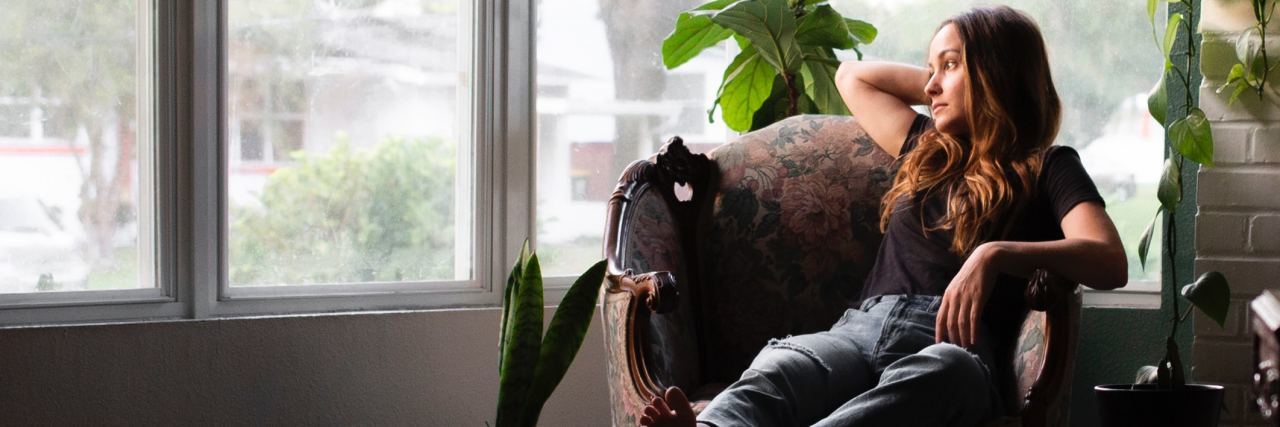 Signs My Depression Is Actually Bipolar Disorder photo of woman looking out of window in dark room