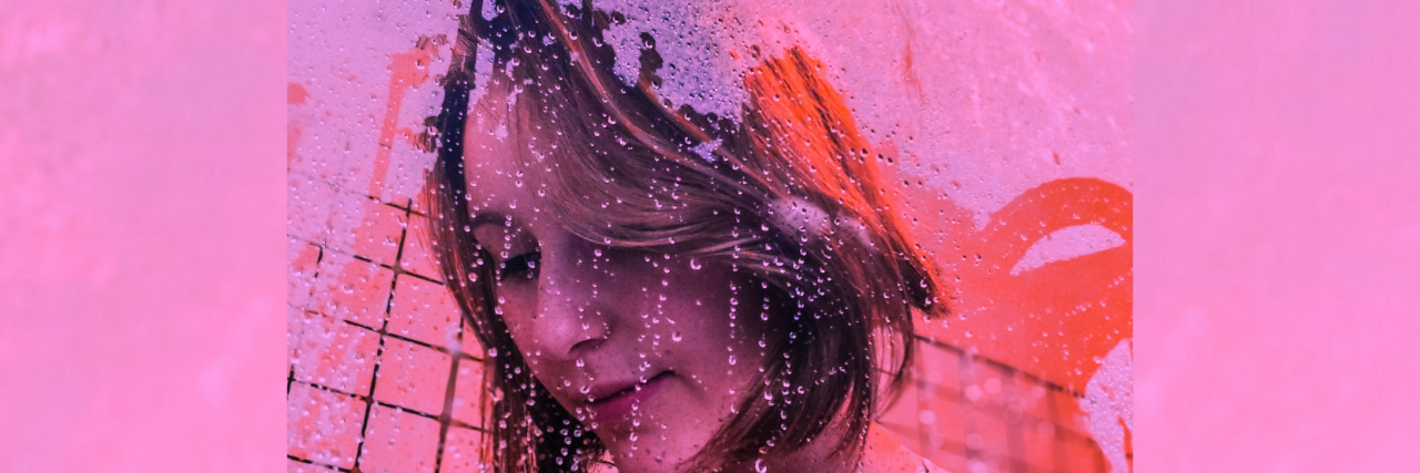 A woman stands in the shower with suds on the shower door, washed out in a vibrant pink. 21 'Weird' Things People With Mental Illness Do In the Shower
