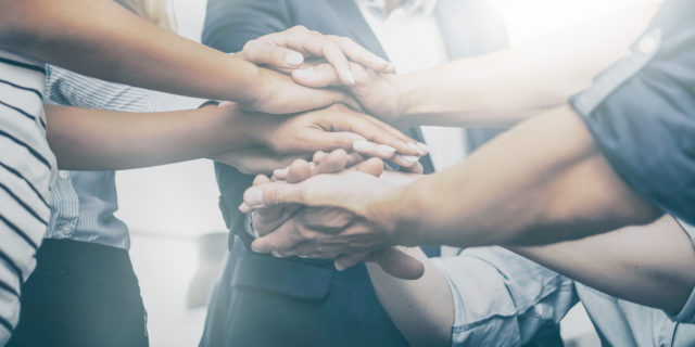 My Community Is the Only Reason I Continue to Fight My Chronic Illness close up view of people stacking their hands on top of one other's