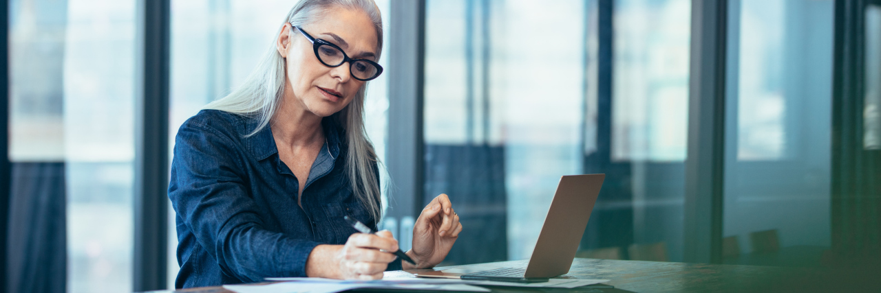 5 Things to Know About Returning to Work After Cancer Treatment Portrait of senior woman sitting at table in office and reading few paper work. Business manager working on some documents at office.