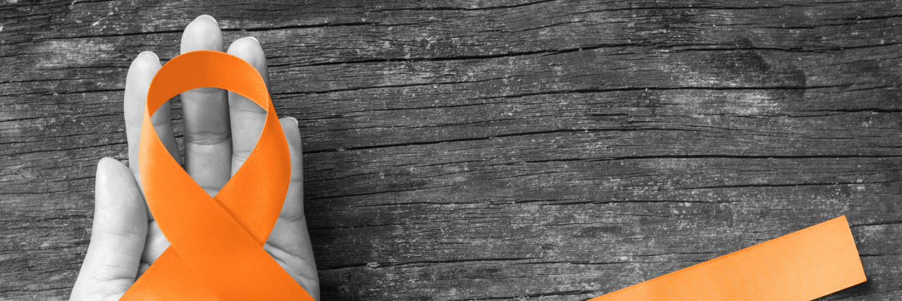 When Multiple Sclerosis Affects Multiple Generations of Your Family Hand holding orange multiple sclerosis awareness ribbon.