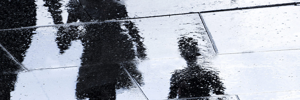 A Letter to My Brother, Who Died by Suicide Blurry reflection shadow silhouette in a puddle of siblings and a parent walking wet city street