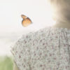 Butterfly landing on a woman's shoulder.
