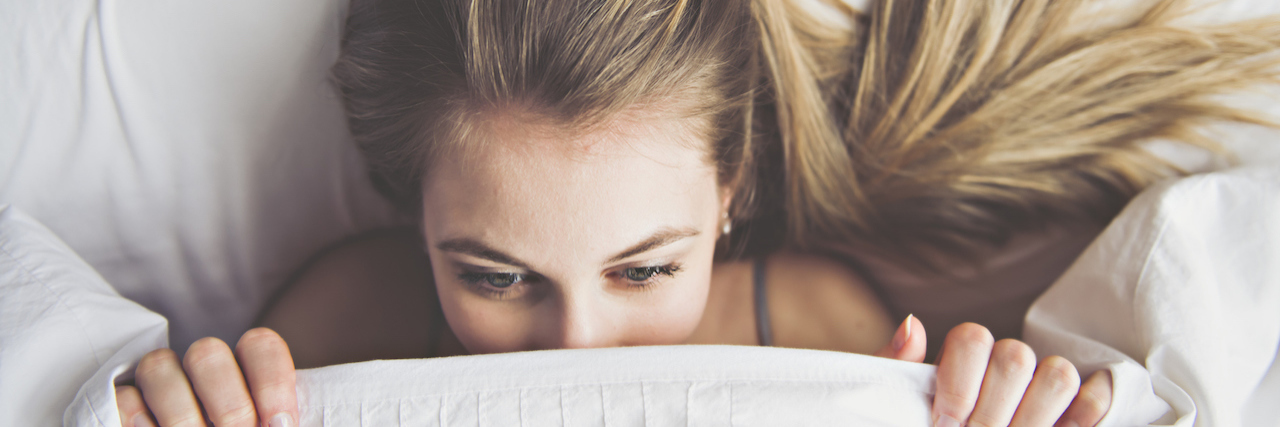 What It's Like to Live With an Anxiety Disorder A woman who just woke up, just barely lifting her head out of bed