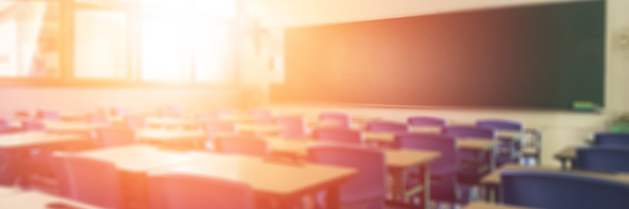 California Teacher With Cancer Must Pay for Substitute Out of Paycheck School classroom in blur background without young student; Blurry view of elementary class room no kid or teacher with chairs and tables in campus.