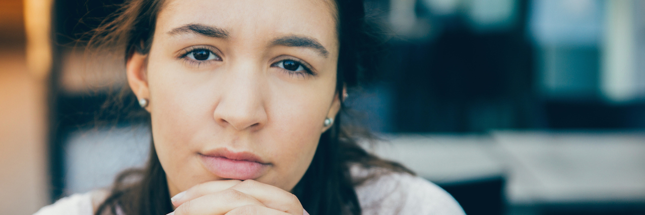 How Developing Multiple Sclerosis Saved My Life A woman looking ahead with her hands clasped