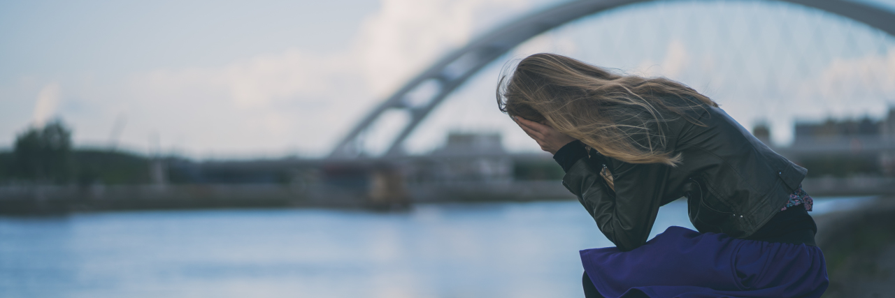Grieving After an Ehlers-Danlos Syndrome Diagnosis Woman crying on a dock by the river.