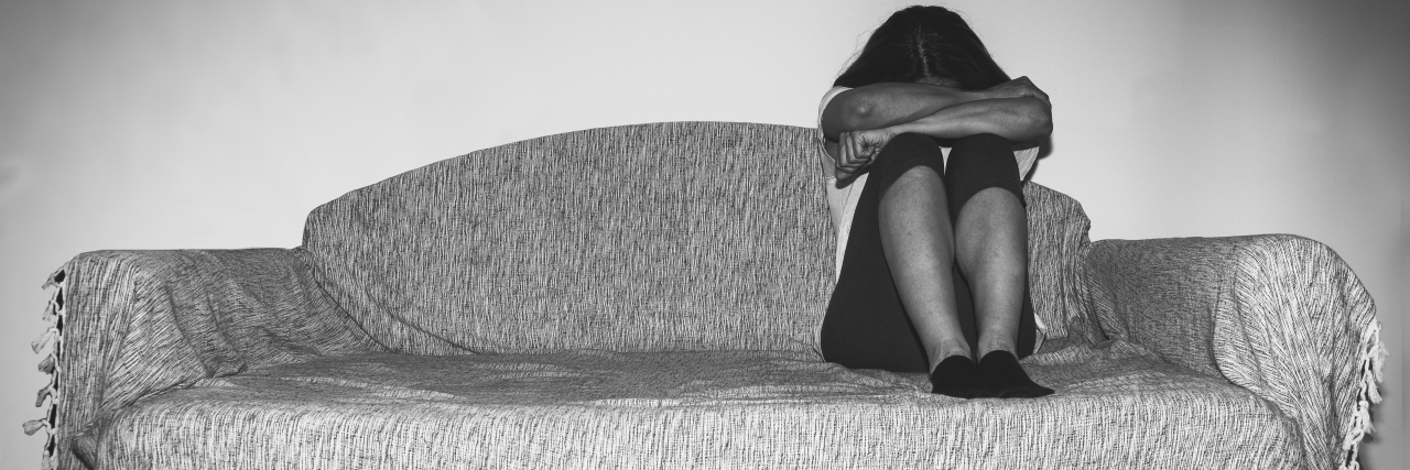 How a Depression Screening Saved My Life a woman sitting on a couch with her head tucked into her arms