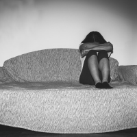 a woman sitting on a couch with her head tucked into her arms
